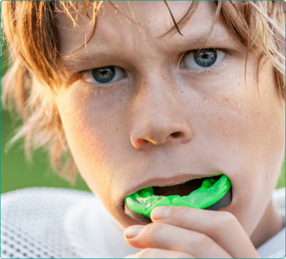 Young boy wearing green athletic mouthguard